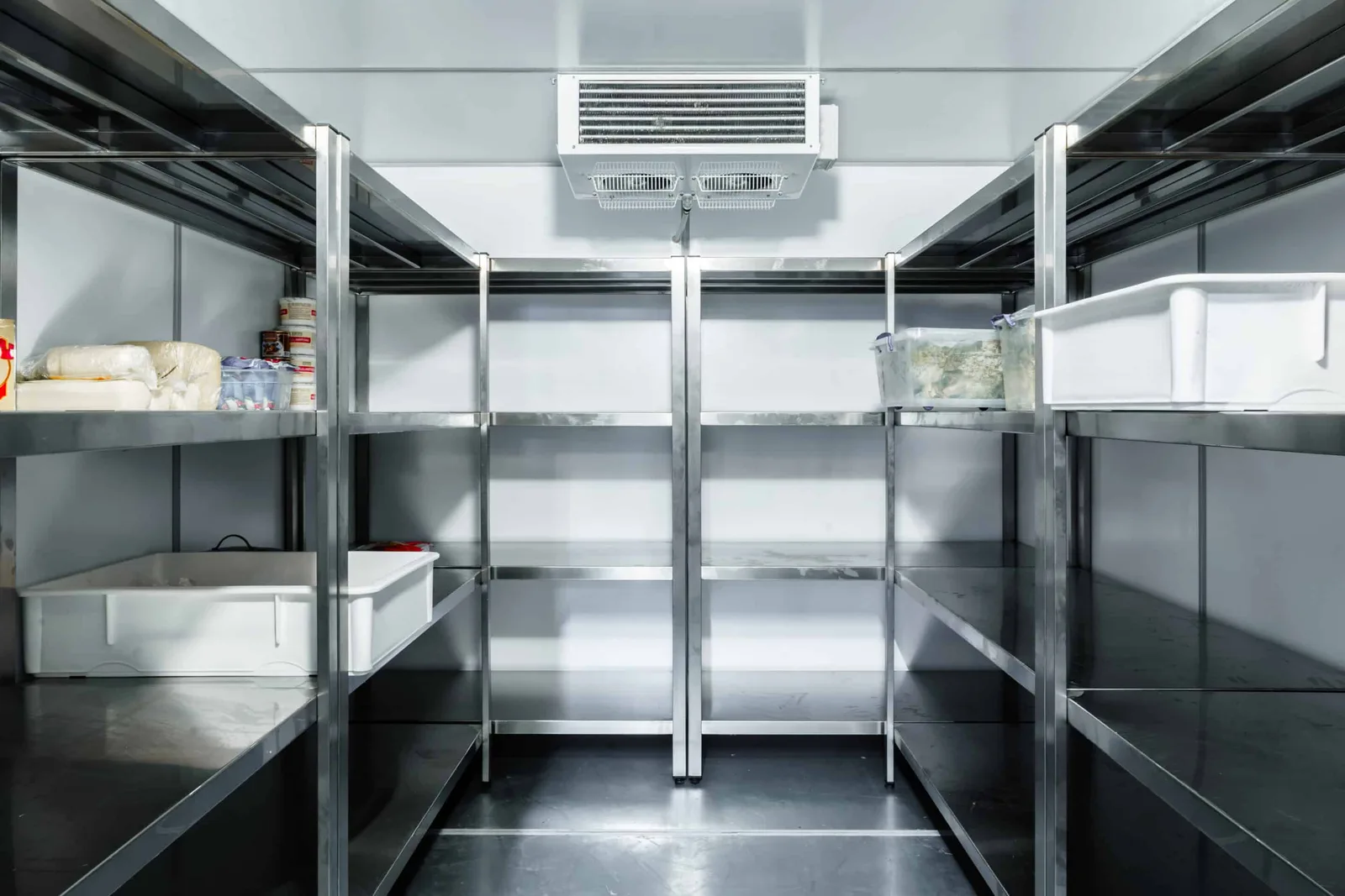 Koelcel van een horecabedrijf met roestvrijstalen stellingen en een verdamper aan het plafond